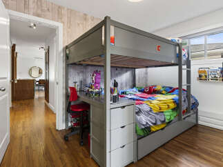 This charming bedroom features a space-saving bunk bed with an integrated desk and storage, perfect for a child's room.