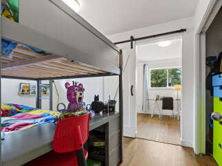 This charming bedroom features a space-saving loft bed with a built-in desk, perfect for maximizing room functionality.
