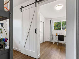 Discover a charming room featuring a stylish white barn door that slides open to reveal a bright workspace.