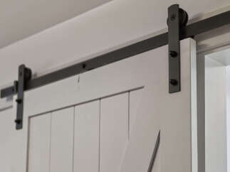 Enhance your home's aesthetic with this stylish white barn door, featuring a sleek black metal sliding track and hardware.