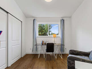This bright and airy room features a sleek glass-top desk with a modern chair, perfect for a home office setup.