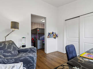 Discover a versatile living space featuring a comfortable armchair and a unique loft bed setup in an adjacent room, perfect for a child's bedroom or a creative studio.