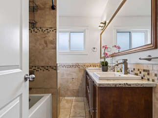 This beautifully updated bathroom features a spacious vanity with dual sinks and granite countertops, perfect for busy mornings.