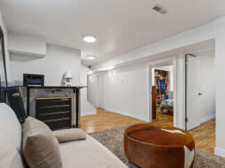 Discover this beautifully finished basement, featuring a spacious living area with a comfortable sofa and a unique cowhide ottoman, perfect for relaxation.