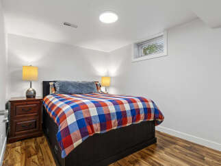 This cozy bedroom features a comfortable queen-size bed with a vibrant plaid comforter, perfect for a restful night's sleep.