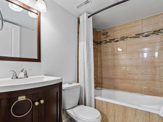 This bathroom features a modern vanity with ample storage and a sleek faucet, complemented by a clean white toilet.