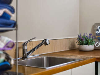 This laundry room features a deep stainless steel sink with a pull-out faucet, perfect for tackling tough stains or washing delicate items.