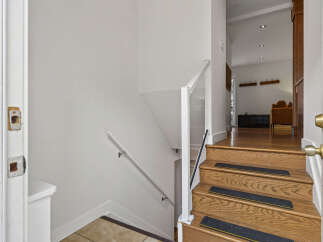 Step into this inviting home and ascend the beautifully crafted wooden staircase, featuring non-slip treads for safety and a modern glass railing.