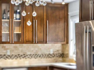 Experience luxury in this stunning kitchen featuring elegant dark wood cabinetry and a sparkling crystal chandelier.