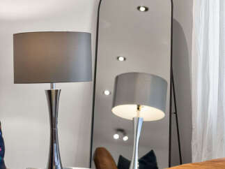 This living room features a sleek, modern aesthetic with a large arched mirror reflecting the space.