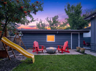 Enjoy evenings in this backyard oasis featuring a modern fire pit surrounded by comfortable Adirondack chairs, perfect for gathering with loved ones.