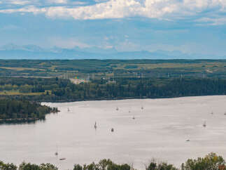 Experience serene lakeside living with this stunning panoramic view, showcasing a tranquil lake dotted with sailboats.