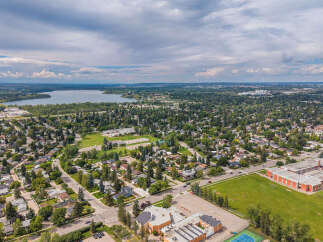 Discover this charming aerial view of a suburban neighborhood, featuring a serene lake in the distance and lush green spaces.