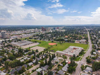 Discover this expansive aerial view showcasing a vibrant community with a prominent school and sports fields at its heart.
