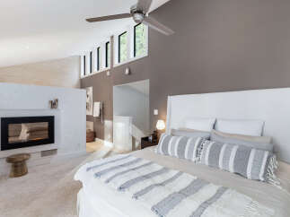 Experience luxury and comfort in this master bedroom, featuring a modern fireplace and a sleek ceiling fan for optimal ambiance.