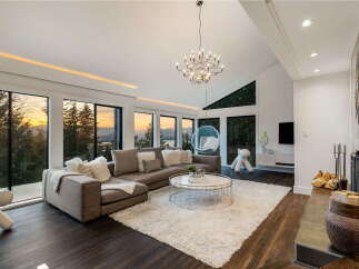 Experience breathtaking sunset views from this luxurious living room, featuring a spacious sectional sofa and a plush white rug.