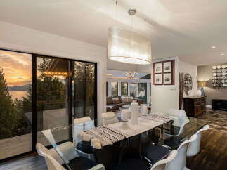 Experience breathtaking sunset views over the water from this stunning dining area, featuring a sleek glass-top table and modern chairs.
