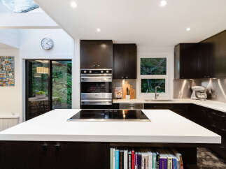 Experience modern living in this stunning kitchen featuring dark wood cabinetry and sleek white countertops.