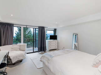 Experience breathtaking mountain and forest views from this serene bedroom, featuring a comfortable seating area and direct balcony access.