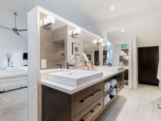 Experience luxury in this modern bathroom featuring a dual vanity with sleek white sinks and dark wood cabinetry.