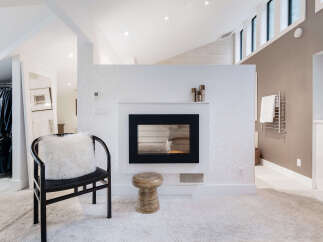 Experience modern luxury in this stunning bedroom featuring a sleek fireplace as the focal point.