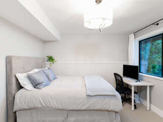 This bedroom offers a comfortable and functional space with a plush upholstered headboard and a cozy duvet.