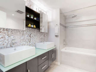 This modern bathroom features a sleek vanity with two vessel sinks and a striking floral wallpaper accent.