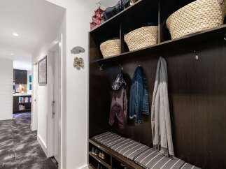 This entryway features a dark wood built-in storage unit with open shelving and a padded bench, perfect for organizing coats, shoes, and accessories.