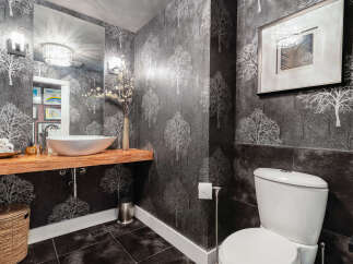 This modern bathroom features a striking charcoal wallpaper with a white tree silhouette pattern, creating a dramatic and elegant ambiance.