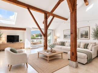 Experience rustic charm and modern comfort in this spacious living room, featuring exposed wooden beams and a vaulted ceiling with a skylight.