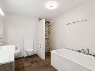 This modern bathroom features a spacious bathtub and a separate shower area with elegant tilework.