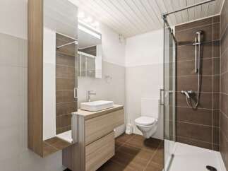 This modern bathroom features a sleek vanity with a vessel sink, complemented by a large mirrored cabinet for ample storage.