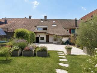 Discover this charming property featuring a spacious backyard with lush green grass and vibrant flower beds.