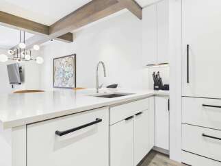 Experience modern luxury in this stunning kitchen featuring sleek white cabinetry and a pristine quartz countertop island.