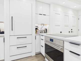 Experience modern living in this stunning kitchen, featuring sleek white cabinetry with minimalist black hardware.