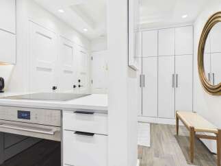 Experience modern living in this sleek kitchen featuring a built-in oven and stovetop, complemented by ample white cabinetry.