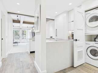 Discover modern living in this beautifully renovated condo, featuring a sleek white kitchen with a waterfall island and integrated appliances.