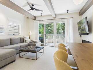 Experience modern mountain living in this beautifully appointed living space, featuring a plush sectional sofa and a stylish tufted ottoman.