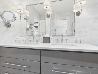 Experience luxury in this modern bathroom featuring a double vanity with sleek grey cabinetry and a white quartz countertop.