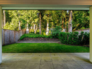 Step out onto a spacious patio overlooking a lush, green backyard perfect for outdoor entertaining.