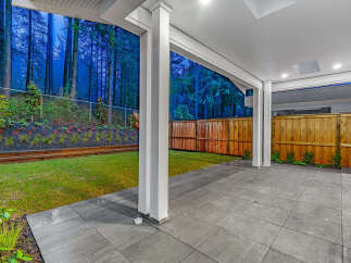 Enjoy the tranquility of this covered patio overlooking a lush, forested backyard.
