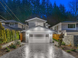 Experience modern luxury in this stunning new construction home, featuring a sleek gray exterior and a spacious two-car garage.