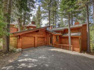 Nestled among tall pine trees, this stunning wooden home offers a rustic yet modern aesthetic.
