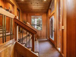 Step into a warm and inviting entryway featuring rich wood paneling throughout, creating a cozy cabin-like atmosphere.