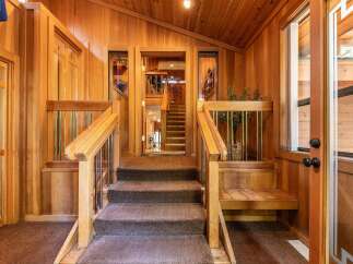 Step into a warm and inviting entryway featuring rich wood paneling and a plush carpeted staircase.