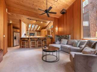 Experience rustic charm in this inviting living space featuring warm wood paneling and a vaulted ceiling with exposed beams.