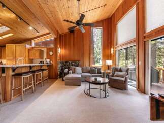 Experience rustic charm in this spacious living area featuring a vaulted wood-paneled ceiling and a cozy stone fireplace.
