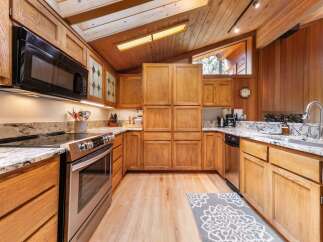 Experience the warmth of this charming kitchen, featuring rich oak cabinetry and a vaulted wood-paneled ceiling that creates an airy, inviting atmosphere.
