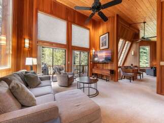Experience rustic charm and modern comfort in this stunning living room, featuring soaring wood-paneled ceilings and a cozy sectional sofa perfect for relaxation.