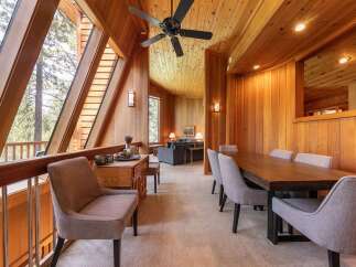 Experience rustic charm in this stunning dining area, featuring a grand wooden table surrounded by comfortable upholstered chairs.